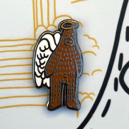 Enamel pin of a stylized sasquatch with wings and sparkly halo closed on a decorative background